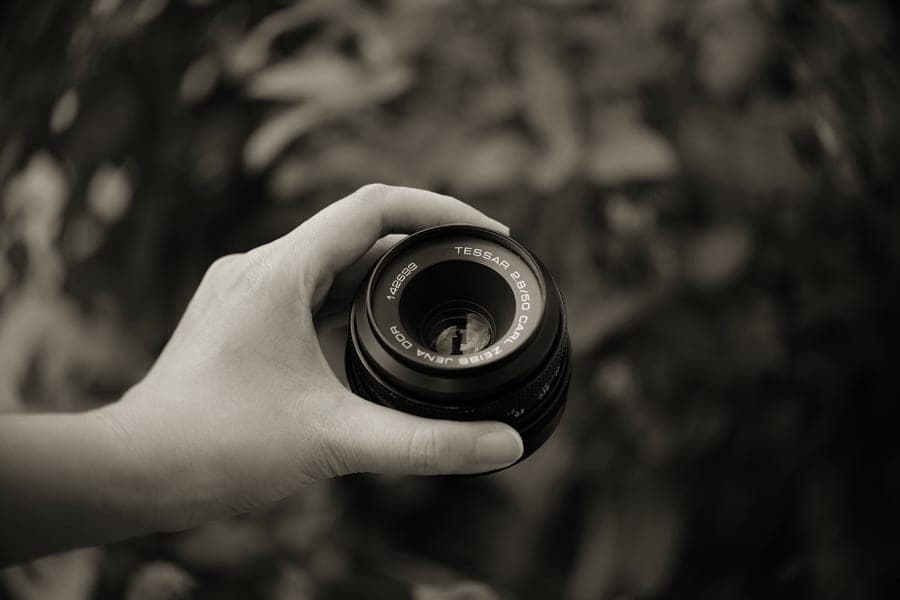 A small instant camera held in one hand beside a fresh print