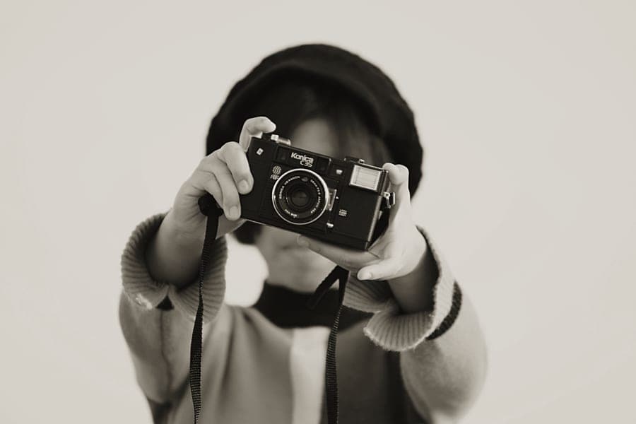 A young person holding a simple instant camera up to take a photograph