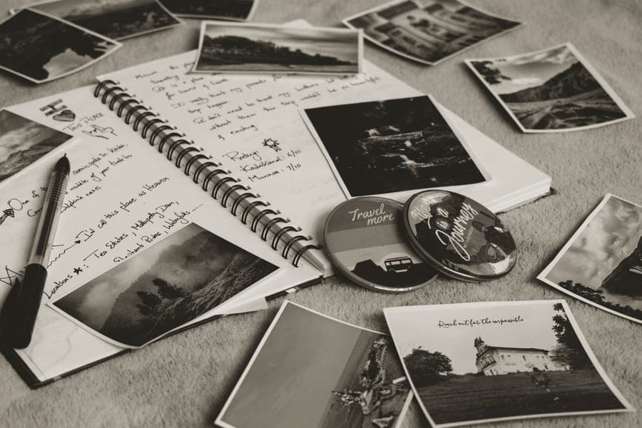 An open scrapbook with small printed photos, tape and scissors