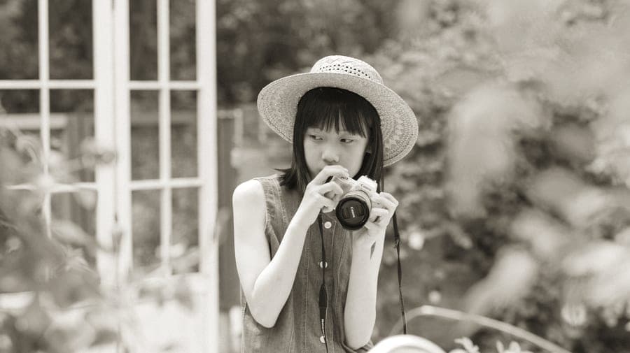 A teenager holding a small camera and looking at a print